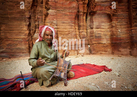 2016-04-27 An old man playing traditional Bedouin Rababa string musical instruments near tomb 67. Ancient city of Petra, Jordan Stock Photo