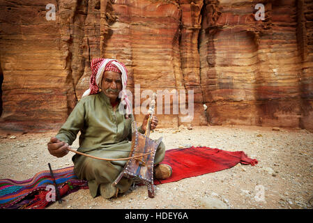 2016-04-27 An old man playing traditional Bedouin Rababa string musical instruments near tomb 67. Ancient city of Petra, Jordan Stock Photo