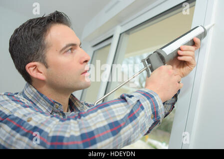 construction worker sealing window in house Stock Photo