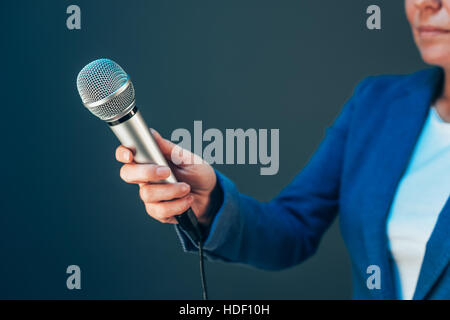 Elegant female journalist conducting business interview, hand with microphone Stock Photo