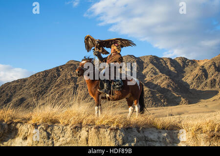 Bayan Ulgii, Mongolia, October 2nd, 2015: Old eagle hunter with his Altai Golden Eagle on his horse Stock Photo