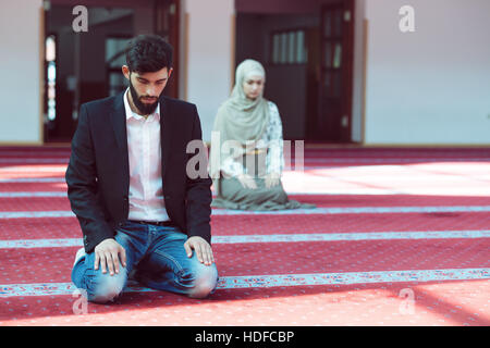 Muslim man and woman praying in mosque Stock Photo