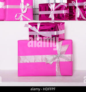 Stack of pink celebration gift boxes with ribbon bows on white table. Winter holidays concept. Stock Photo