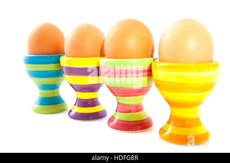 Four colorful striped eggcups in a row isolated over white Stock Photo