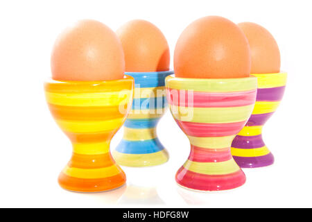 Four colorful striped eggcups in a row isolated over white Stock Photo