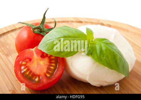 Mozzarella on a wooden plate with tomato and basil Stock Photo