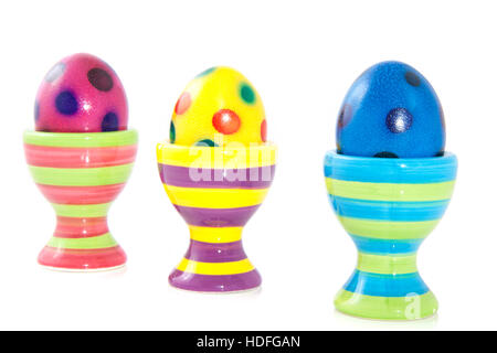 Colorful spotted eggs in striped eggcups isolated over white Stock Photo