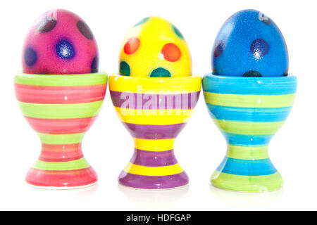 Colorful spotted eggs in striped eggcups isolated over white Stock Photo