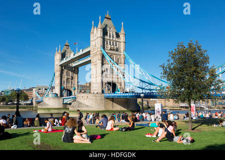 LONDON, The Queen's South Bank Walk London. Tourists enjoy sun and shade by Tower Bridge on the Southbank of the Thames Stock Photo
