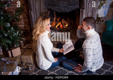 Couple relaxing at home reading a book. Feet in wool socks near fireplace. Winter holiday concept Stock Photo