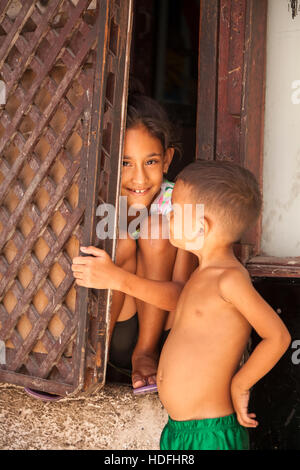 Two children, one is hiding behind a door in Central Havana, Cuba. Stock Photo