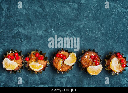 cupcakes in tins ,decorated with berries and slice of tangerine Stock Photo