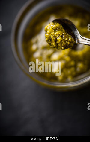 Pesto sauce in the metal spoon with blurred jar vertical Stock Photo