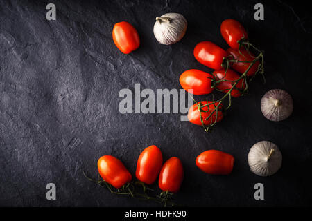 Cherry tomatoes with garlic on the black stone table Stock Photo