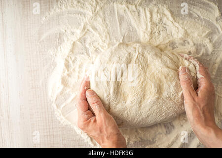 Dough  in the hand on the table with flour top view Stock Photo