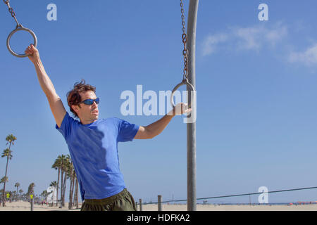 young man using rings at santa monica beach in los angeles california Stock Photo