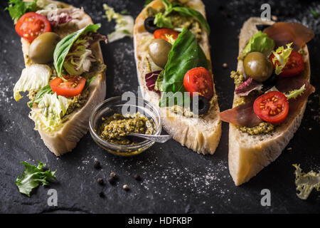 Ciabatta with olives , tomatoes and basil on the black stone table Stock Photo