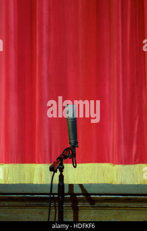 single microphone in front of red stage curtain Stock Photo