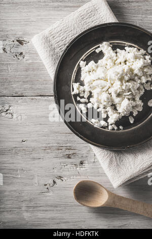 Fresh cottage cheese on the  metal plate on the white wooden table vertical Stock Photo