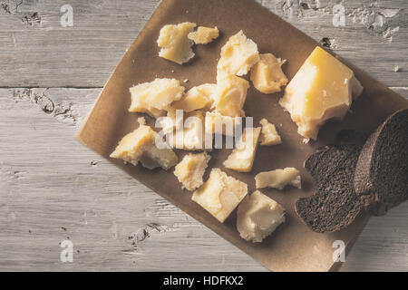 Sliced parmesan with bread on the parchment on the white wooden table top view Stock Photo