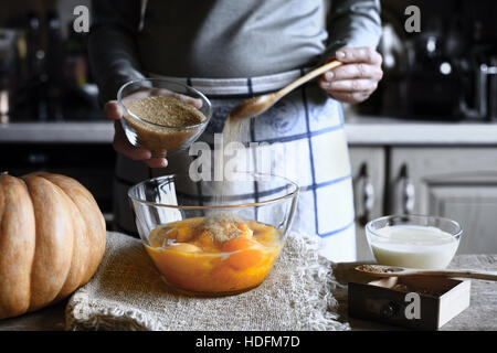 Adding brown sugar in the dough for pumpkin dump cake Stock Photo