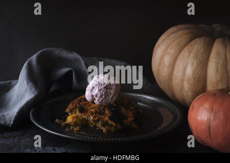 Pumpkin dump cake with ice cream on the metal plate on the stone table Stock Photo