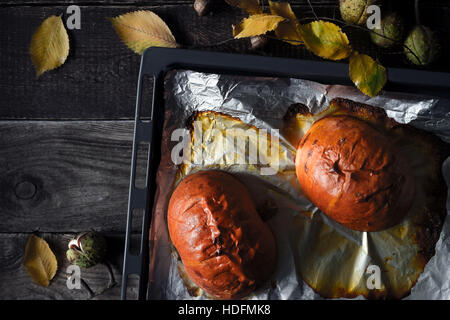 Halves of baked pumpkin on the baking tray on the wooden table top view Stock Photo