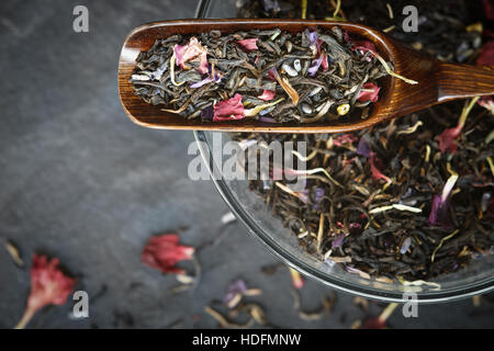 Black tea with flower  petals in the wooden spoon top view Stock Photo