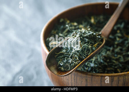 Tea leaves on the wooden bowl on the  dark stone background horizontal Stock Photo