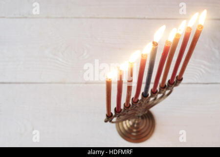 Hanukkah menorah with burning candles on the white wooden table Stock Photo
