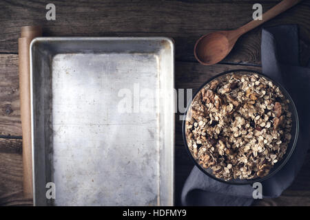 Granola in the glass bowl with baking tray on the wooden table top view Stock Photo