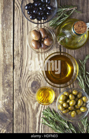 Olives with olive oil and rosemary on the wooden table Stock Photo