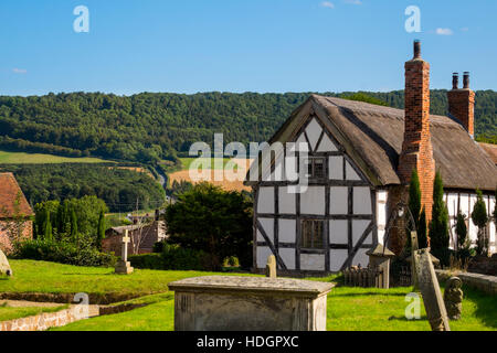 Black and White thatched cottage at Harley, Shropshire, with Wenlock Edge in the background, England, UK Stock Photo