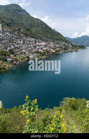 Distant view of San Antonio Palopo, Guatemala, on the shore of Lake Atitlan.  Steep hillsides drop into the lake, which is an extinict volcanic crater Stock Photo