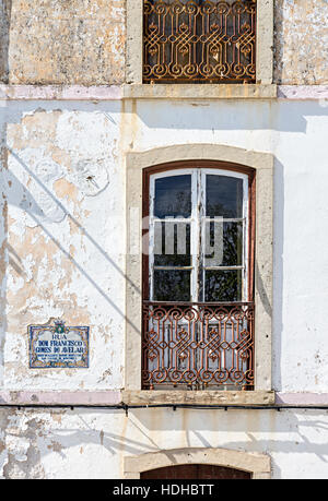 Window and street name: first floor house window and grille with street sign tiles, Monchique, Algarve, Portugal Stock Photo
