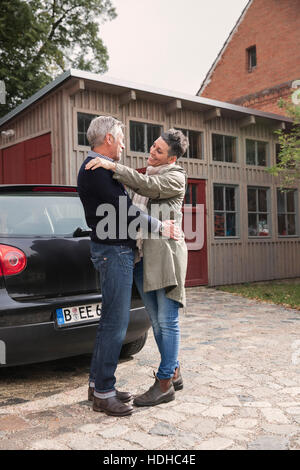 Happy couple embracing by car against house Stock Photo