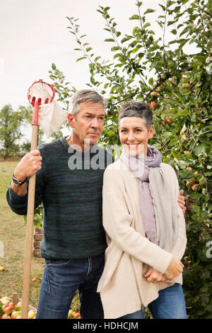 Portrait of happy woman standing with man in apple orchard Stock Photo
