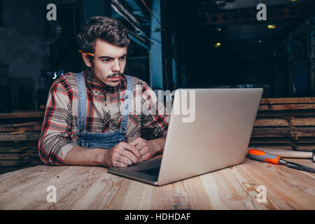 Carpenter using laptop while sitting in workshop Stock Photo