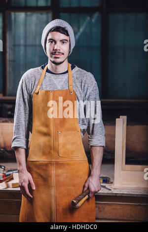 Portrait of carpenter holding hand tools at workshop Stock Photo