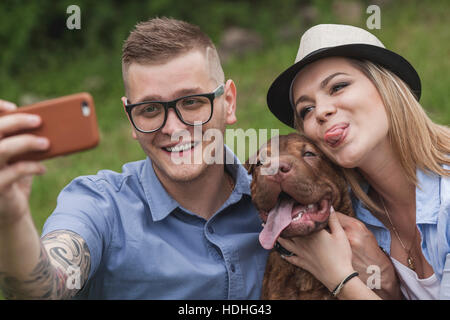 A couple with their Shar-pei/Staffordshire Terrier dog at the park taking a selfie Stock Photo