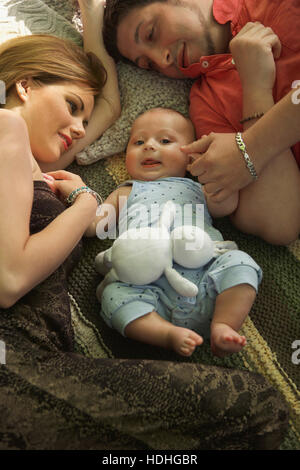 High angle view of cute baby boy lying with parents on bed at home Stock Photo