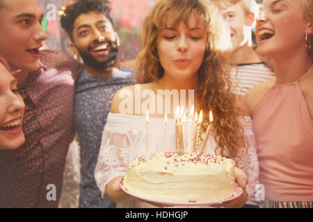 Woman blowing candles while celebrating birthday with friends Stock Photo