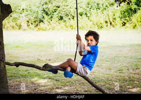 Portrait of young boy sitting on a tree swing. Stock Photo