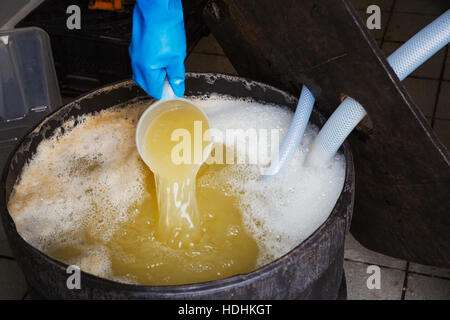 A person with a jug pouring freshly pressed apple juice into a container. Stock Photo