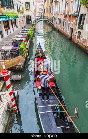 Gondola with tourists in the canals of Venice, Italy.