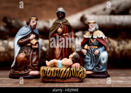 closeup of the three kings carrying their gifts adoring the Child Jesus on a rustic scene Stock Photo