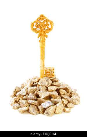 Golden key on a pile golden stones isolated over white Stock Photo