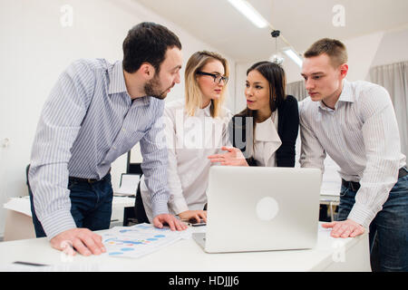 Colleagues at an office meeting talking and working on a laptop Stock Photo