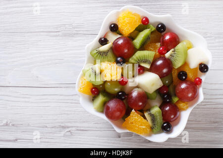 Fruit salad of oranges, grapes. pears, kiwi in white plate close up. horizontal view from above Stock Photo