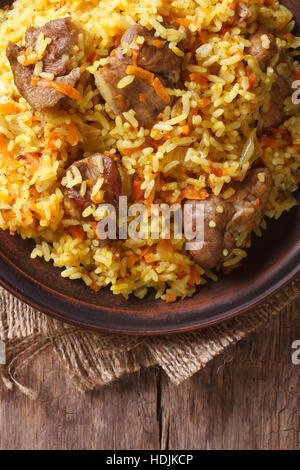Rice with meat and vegetables on an old table macro. vertical view above, rustic style Stock Photo